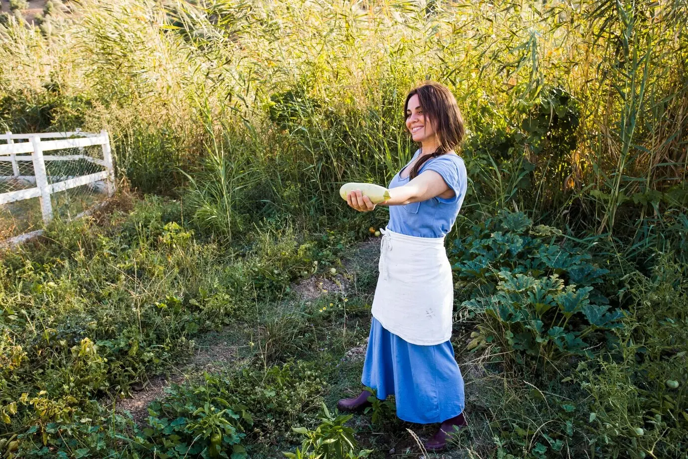 Agricultora sonriente mostrando una calabaza en la mano